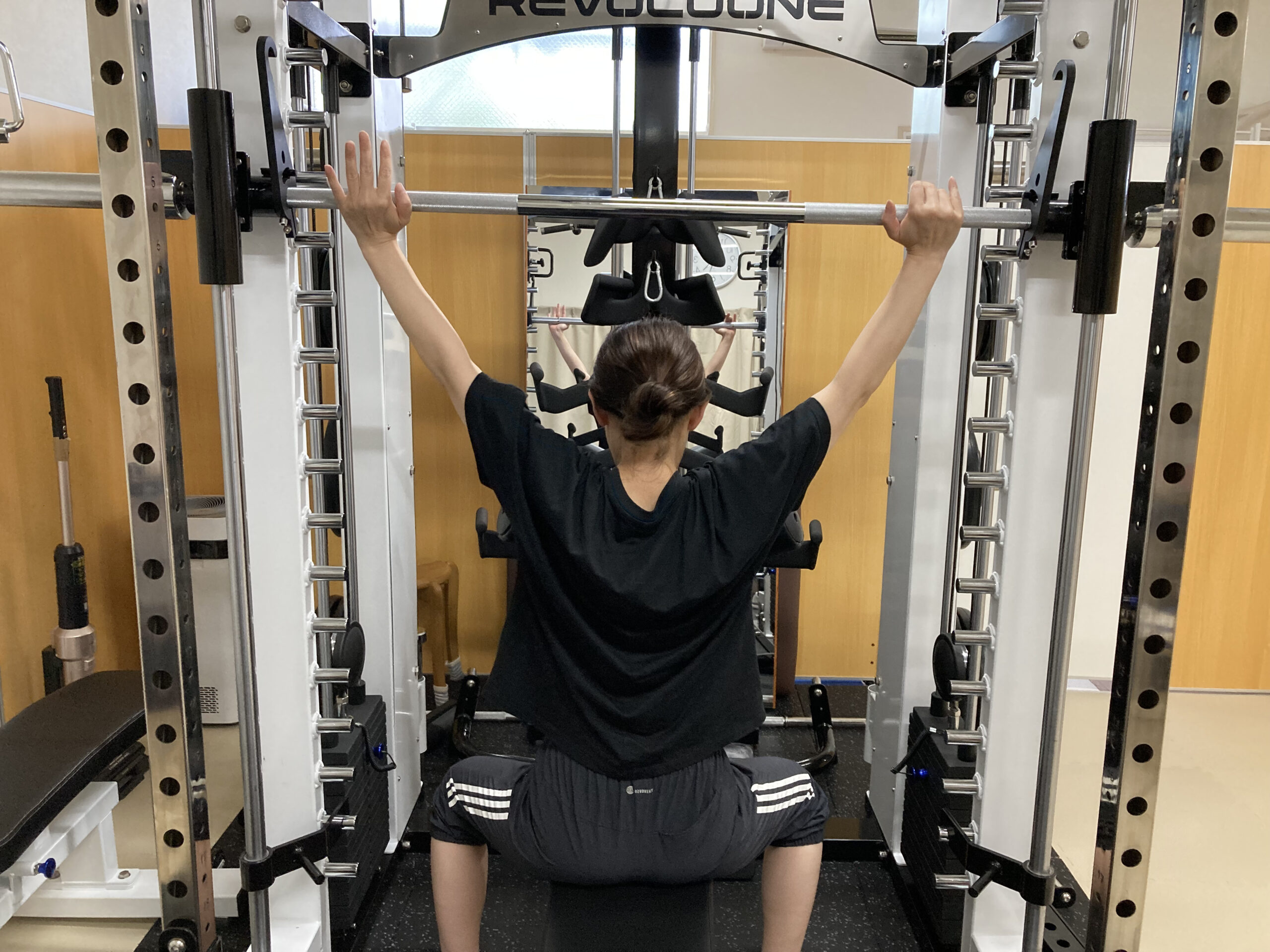 高機能スミスマシンでバーベルをあげる女性